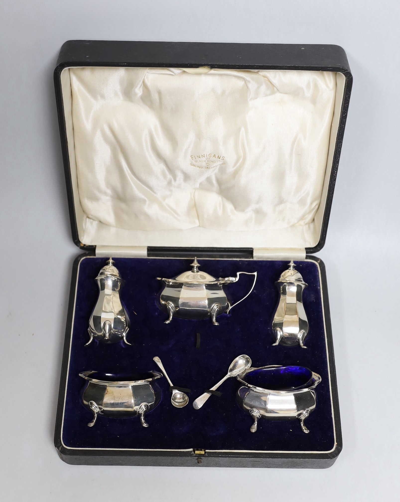 A cased George V silver five piece condiment set, Birmingham, 1921, with two associated spoons, one silver and one plated.